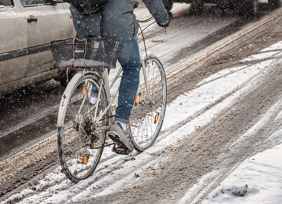 Radfahren im Winter Radfahrer*in fährt auf einer ungeräumten Fahrbahn